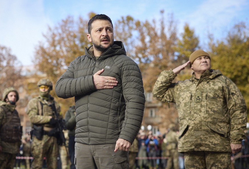In this photo provided by the Ukrainian Presidential Press Office, Ukrainian President Volodymyr Zelenskyy listens to the national anthem during his visit to Kherson, Ukraine, Monday, Nov. 14, 2022. U ...