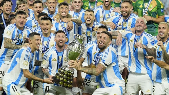 Argentina players Angel di Maria, left, Lionel Messi, second from left, and Nicolas Otamendi, third from left, celebrate with the trophy after defeating Colombia in the Copa America final soccer match ...
