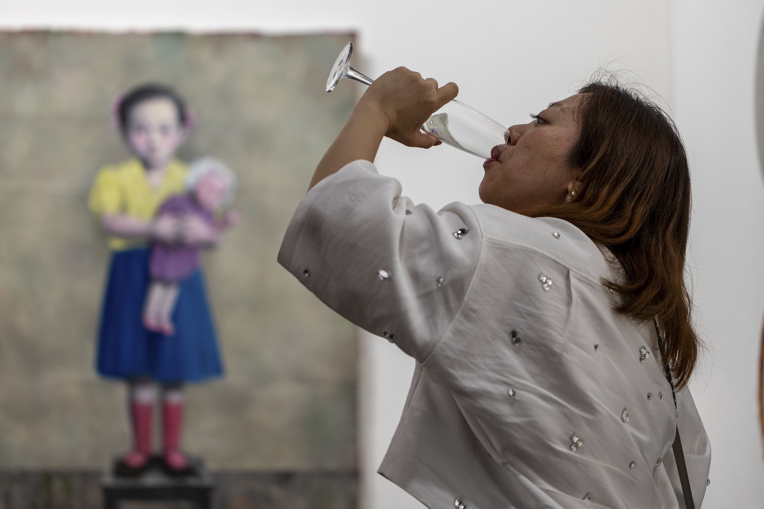 A women drinks from a glass near an artwork at Art Basel in Hong Kong, Wednesday, March 26, 2025. (AP Photo/Vernon Yuen)
Hong Kong Art Basel