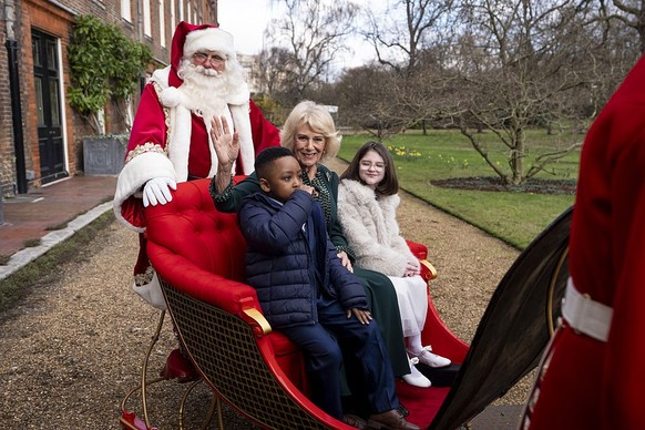 LONDON, ENGLAND - DECEMBER 11: A person dressed as Father Christmas, Queen Camilla Samuel (left) and Myla (right) on the State Sleigh in the gardens of Clarence House, London, during the Christmas tre ...