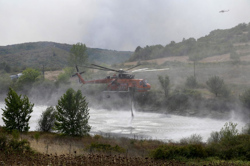 Un hélicoptère de lutte contre les incendies recueille de l'eau près d'un feu de forêt dans la région de Soufli.