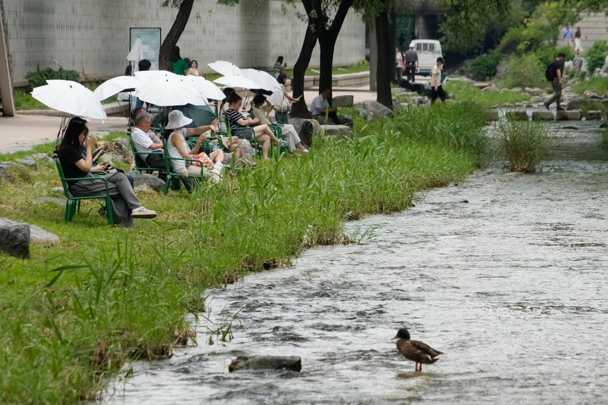 People sit on chairs around the Cheonggye Stream on a sweltering day in Seoul, South Korea, Wednesday, June 17, 2026. (AP Photo/Ahn Young-joon)