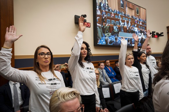 Survivors of convicted sex trafficker Jeffrey Epstein stand in the audience where Attorney General Pam Bondi testifies before the House Judiciary Committee over the Justice Department's handling  ...