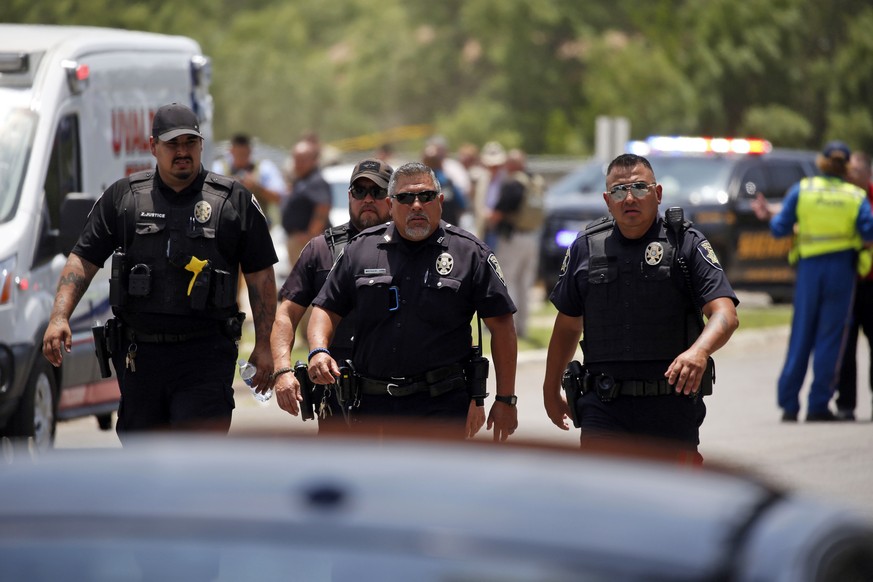 FILE �?? Police walk near Robb Elementary School following a shooting, May 24, 2022, in Uvalde, Texas. Weeks after the shooting, questions remain about how and why police armed with rifles and bulletp ...