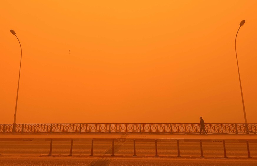 epaselect epa09951009 An Iraqi man walks over the al-Shuhadaa bridge shrouded in heavy dust in central Baghdad, Iraq, 16 May 2022. The dust storm sent thousends of people with respiratory problems to ...