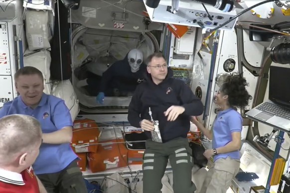 This image provided by NASA shows astronaut Nick Hague greeting the arriving SpaceX Dragon Capsule wearing a grey alien mask after a SpaceX capsule docked with the International Space Station, Sunday, ...