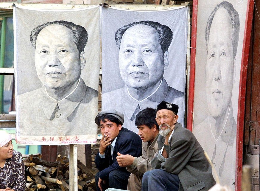 Three Muslim Uighur men rest outside a store where they sell portraits and memorabilia of late communist leader Chairman Mao Zedong, in Kashgar, in China&#039;s western Xinjiang province in this Sept. ...