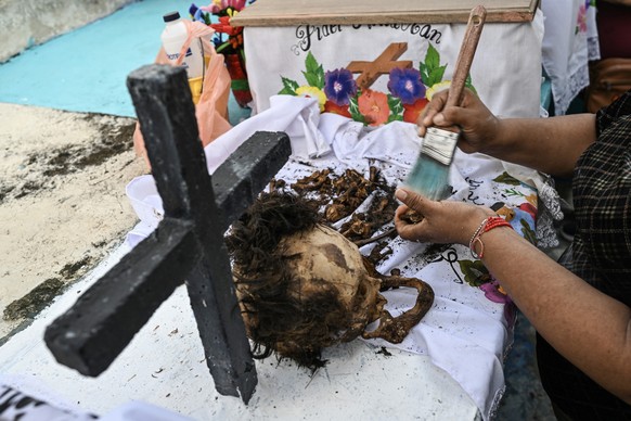 A woman cleans the remains of a relative ahead of Day of the Dead celebrations at the Pomuch cemetery, Campeche state, Mexico on October 18, 2025. The cleansing ritualówhich combines Mayan and Catholi ...