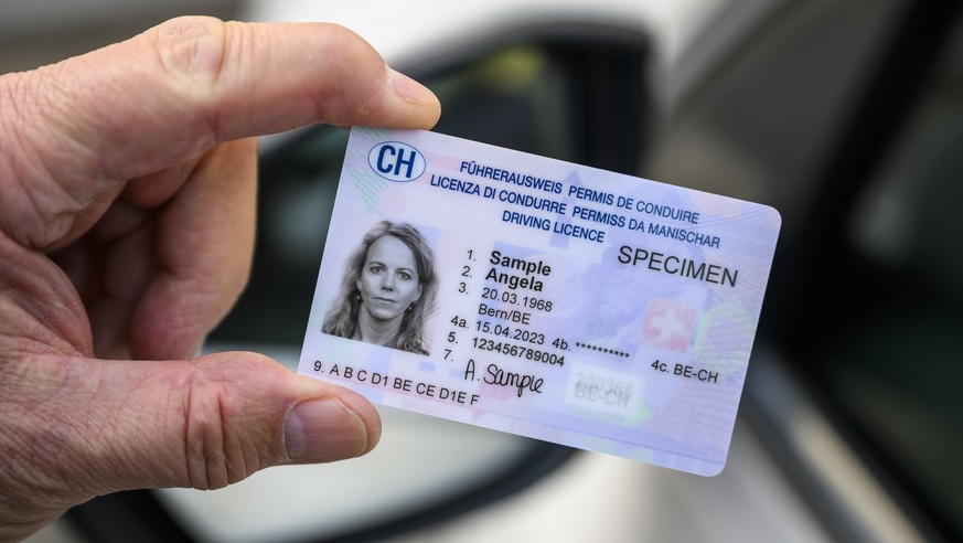 Un specimen du nouveau permis de conduire suisse a haut niveau de securite (Fuehrerausweis) est photographie devant un vehicule le mercredi 5 avril 2023 a Lausanne. (KEYSTONE/Jean-Christophe Bott)