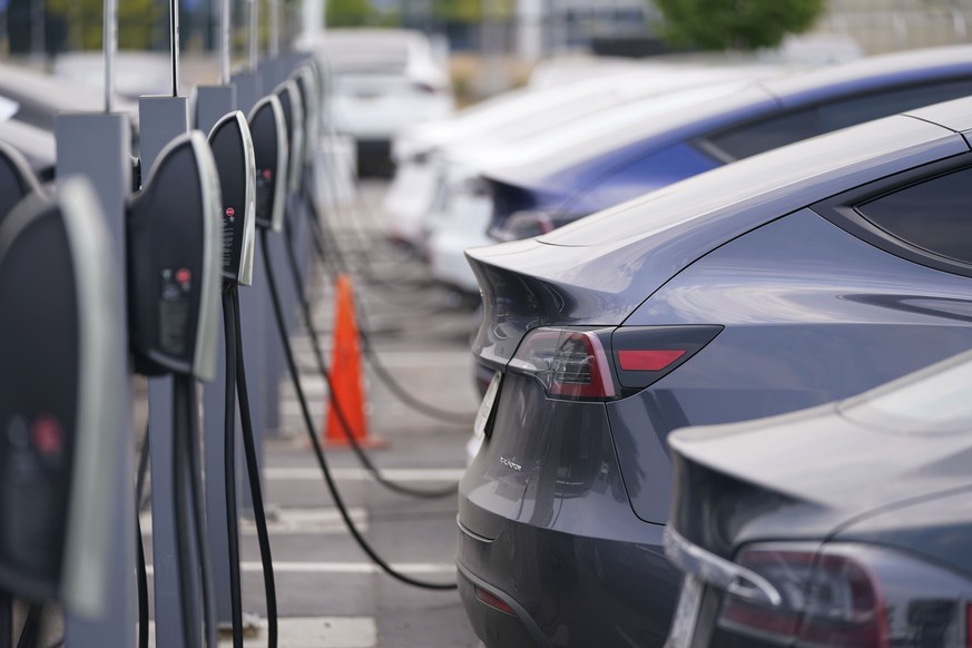 FILE - This Aug. 23, 2020 photo shows a long line of unsold 2020 models charge outside a Tesla dealership in Littleton, Colo. Starting Jan. 1, 2023, many Americans will qualify for a tax credit of up  ...