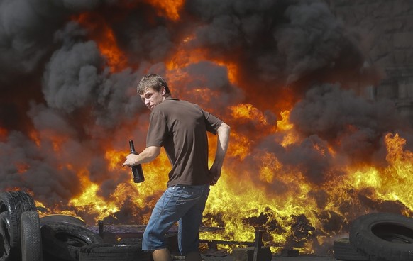 epa04343980 A Maidan activist holds a Molotov cocktail in front of a burning barricade during a protest against Ukrainian authorities trying to clean the main Kiev&#039;s street of Khreschatyk near th ...