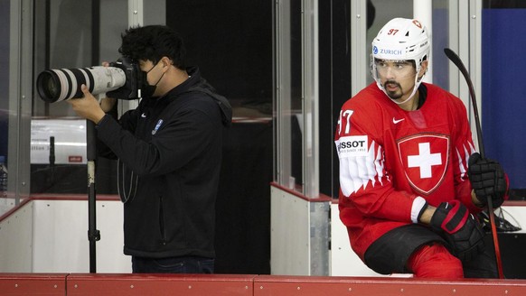 Switzerland&#039;s defender Jonas Siegenthaler, right, seats on the board looks the game next to a IIHF&#039;s photographer, during the IIHF 2021 World Championship preliminary round game between Swit ...