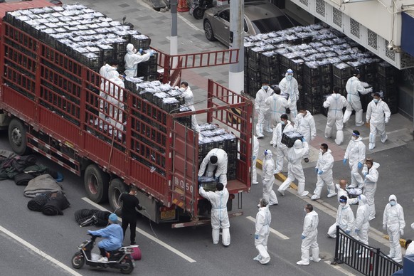 FILE - Workers in PPE unload groceries from a truck before distributing them to local residents under the COVID-19 lockdown in Shanghai, China, on April 5, 2022. Residents of Shanghai are struggling to get meat, rice and other food supplies under anti-coronavirus controls that confine most of its 25 million people in their homes, fueling frustration as the government tries to contain a spreading outbreak.(Chinatopix Via AP, File)