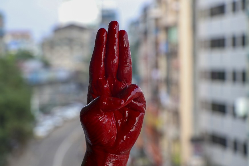 An anti-coup protester shows the three fingered salute of resistance on his red painted hand in memory of protesters who lost their lives during previous demonstrations in Yangon, Myanmar on Tuesday,  ...