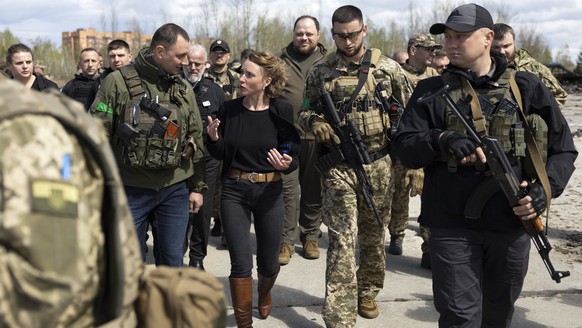 Irene Kaelin, President of the Swiss National Assembly, center, surrounded by members of the Ukrainian military, leaves the Hostomel airfield near Kiev, Ukraine, which was destroyed by Russian invader ...