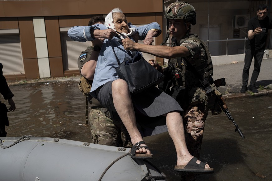 A woman is evacuated from a flooded neighborhood in Kherson, Ukraine, Wednesday, June 7, 2023 after the walls of the Kakhovka dam collapsed. Residents of southern Ukraine braced for a second day of sw ...