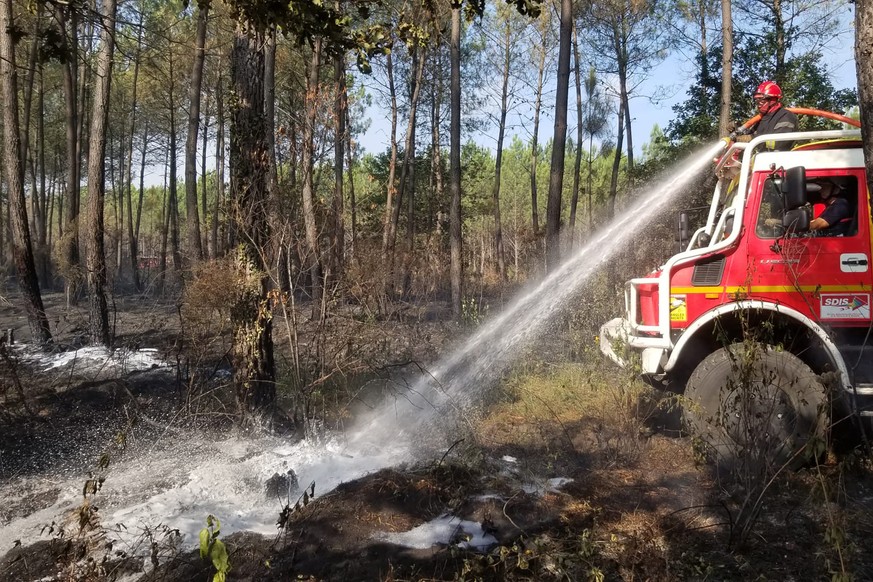 This photo provided by the SDIS33 fire brigade shows firemen watering embers in a forest near Saumos, southwestern France, Thursday, Sept.15, 2022. A major wildfire that ravaged forests in southwester ...