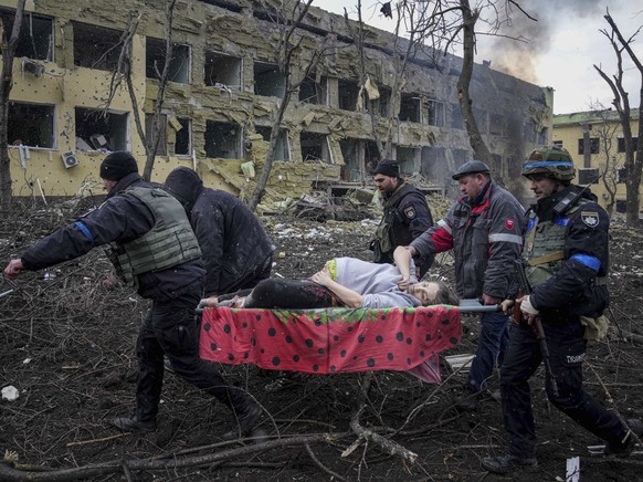 FILE - Ukrainian emergency employees and volunteers carry an injured pregnant woman from a maternity hospital that was damaged by shelling in Mariupol, Ukraine, March 9, 2022. The woman and her baby d ...