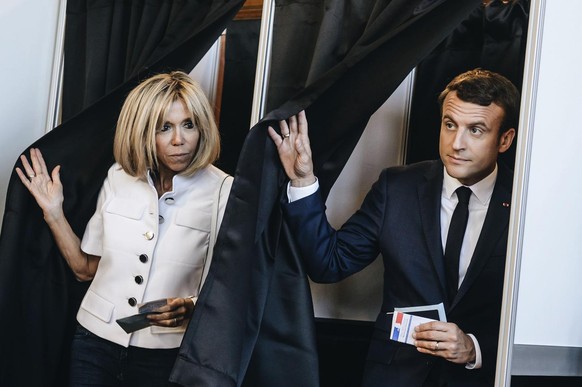 French President Emmanuel Macron and his wife Brigitte Macron leave a polling booth as they vote in the first round of the two-stage legislative elections, in Le Touquet, northern France, Sunday, June ...