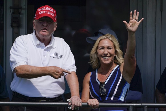 U.S. Rep. Marjorie Taylor Greene waves while former President Donald Trump points to her while they look over the 16th tee during the second round of the Bedminster Invitational LIV Golf tournament in ...