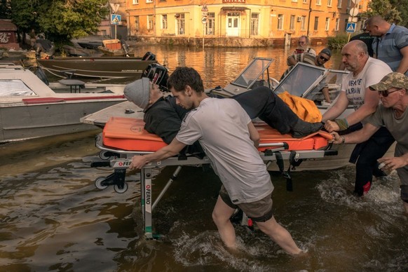 KHERSON, UKRAINE - JUNE 09: Volunteers and others push a stretcher carrying an elderly person who was evacuated from a flooded area on June 9, 2023 in Kherson, Ukraine. Early Tuesday, the Kakhovka dam ...