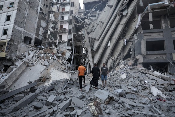 epa10907925 Palsetinians inspect the damage in the surrounding of the destroyed National Bank building following Israeli air strikes, in Gaza City, 08 October 2023. The air strikes in retaliation for  ...