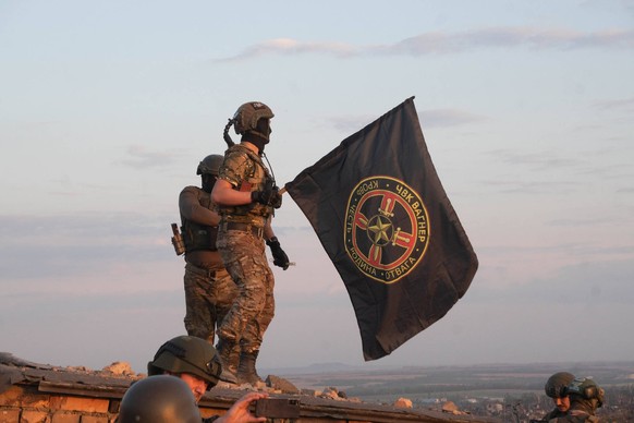 Des combattants de Wagner hissent le drapeau de la milice sur un toit de Bakhmout.