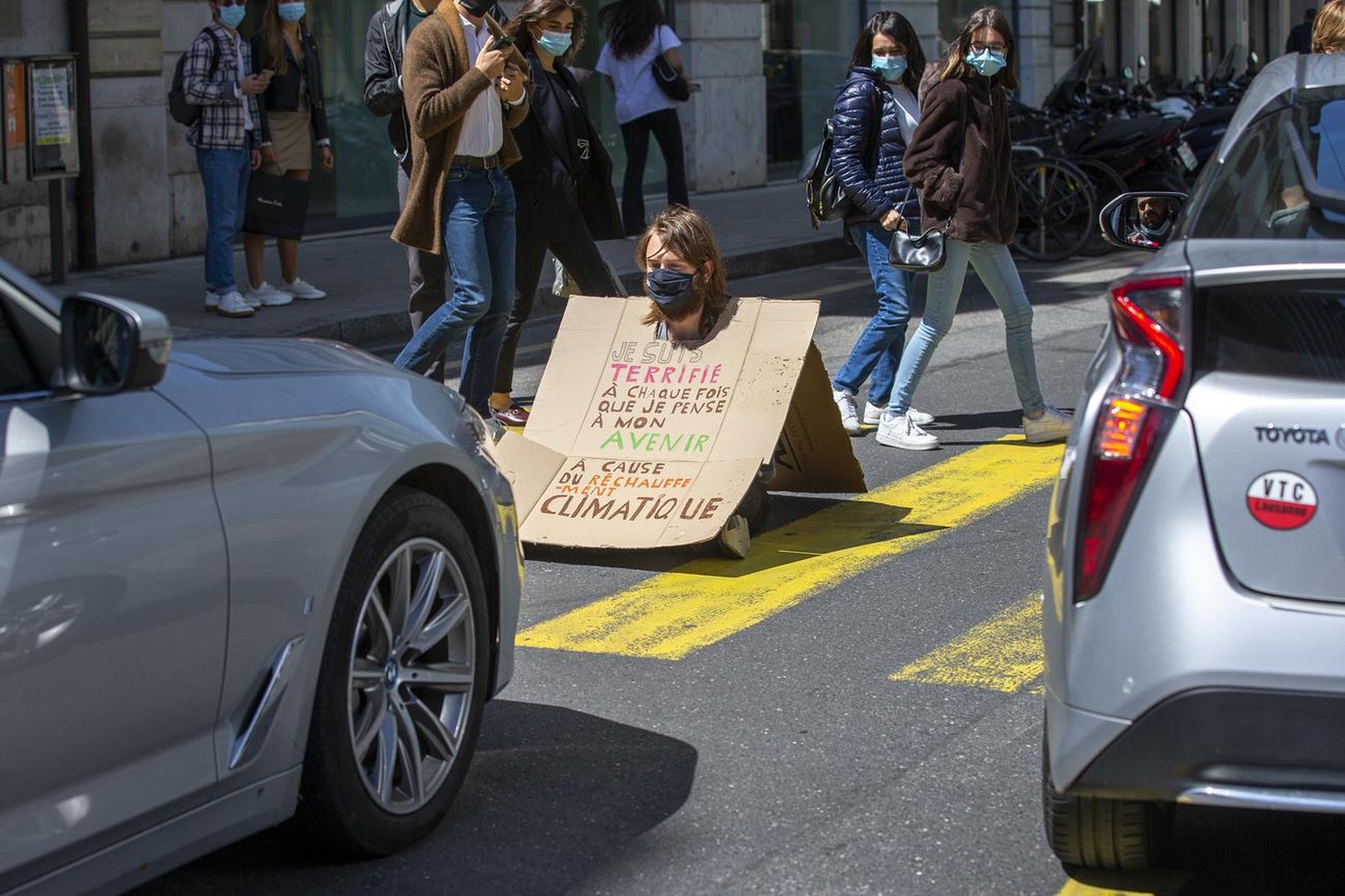 Un militant d&#039;Extinction Rebellion (XR) assis sur la route face a une voiture tenant une pancarte avec le message &quot;Je suis terrifie a chaque fois que je pense mon avenir a cause du rechaufem ...