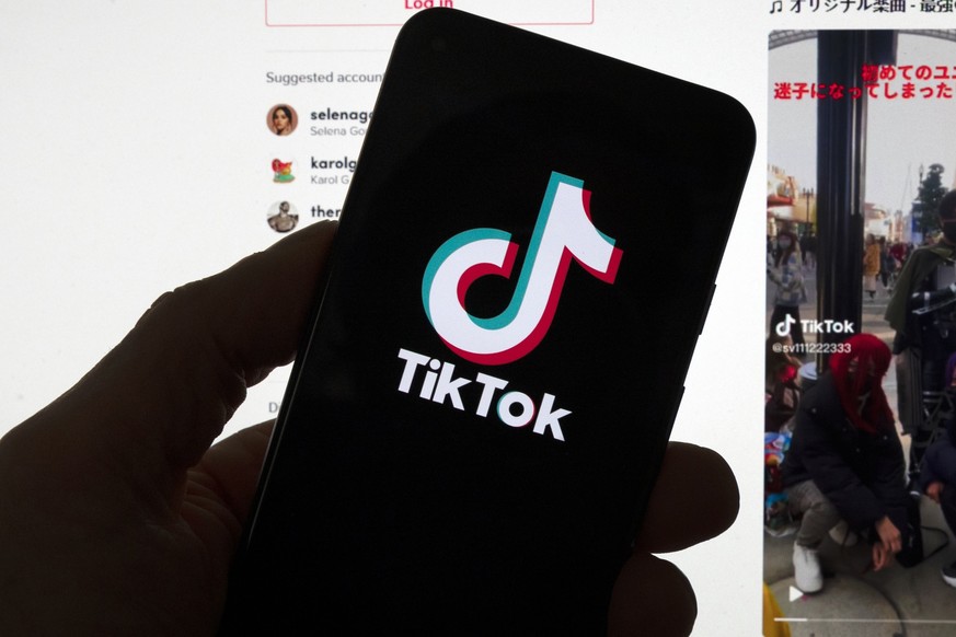 FILE - The TikTok logo is seen on a mobile phone in front of a computer screen which displays the TikTok home screen, Saturday, March 18, 2023, in Boston. TikTok&#039;s CEO plans to tell Congress that ...