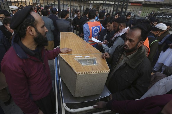 People wait for transport next to a coffin of their relative, killed in the suicide bombing inside a mosque, after collecting from a hospital, in Peshawar, Pakistan, Monday, Jan. 30, 2023. A suicide b ...