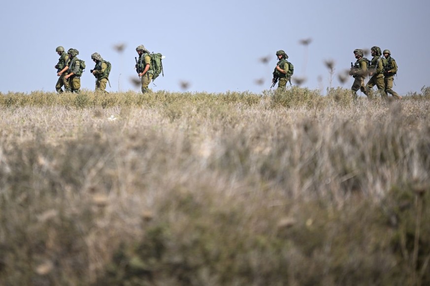 NETIVOT, ISRAEL - OCTOBER 11: Israel Defense Forces soldiers march through a field near the outskirts of Netivot and near an Artillery position on October 11, 2023 in Netivot, Israel. Israel has seale ...