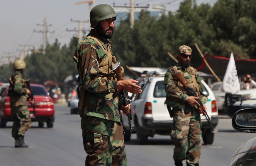 Des talibans, portant l'uniforme aux couleurs de l'ancienne armée afghane, montent la garde à un poste de contrôle routier à Kaboul.