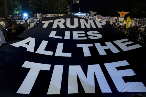 epa08797234 People hold a banner that reads &#039;Trump Lies All The Time&#039;, at Black Lives Matter Plaza near the White House, seen behind, in Washington, DC, USA, 03 November 2020. Americans vote ...