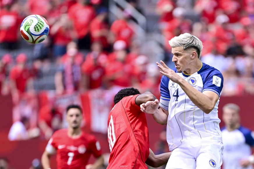 epa13033629 Tarik Muharemovic of Bosnia and Herzegovina in action against Jonathan David of Canada (L) during the FIFA World Cup 2026 group stage match Canada against Bosnia and Herzegovina, in Toront ...