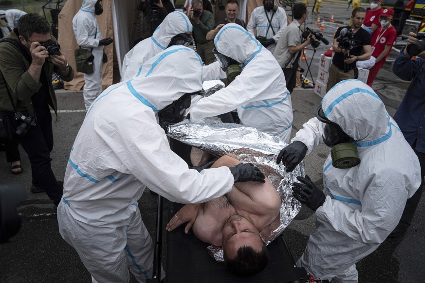 Des secouristes ukrainiens portant des combinaisons de protection contre les radiations recouvrent un homme d'une couverture lors d'une formation à Zaporijia, en Ukraine, le jeudi 29 juin 2023.