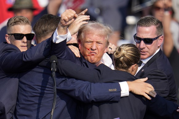 Republican presidential candidate former President Donald Trump pumps his fist as he is helped off the stage at a campaign event in Butler, Pa., on Saturday, July 13, 2024. (AP Photo/Gene J. Puskar)
E ...