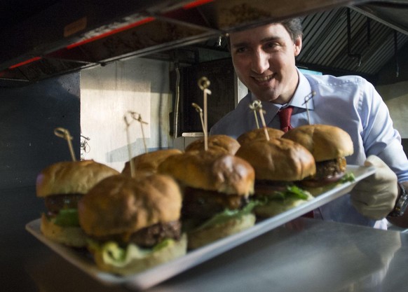 Liberal Leader Justin Trudeau delivers a plate of hamburgers he has just prepared during a campaign event at a bar Tuesday, Oct. 13, 2015 in Toronto. (Paul Chiasson/The Canadian Press via AP) MANDATOR ...