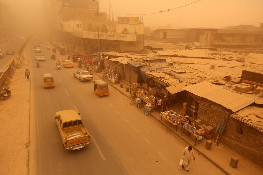 epa09951008 Cars drive along a street at the Shorja market shrouded in heavy dust in central Baghdad, Iraq, 16 May 2022. The dust storm sent thousends of people with respiratory problems to hospitals ...