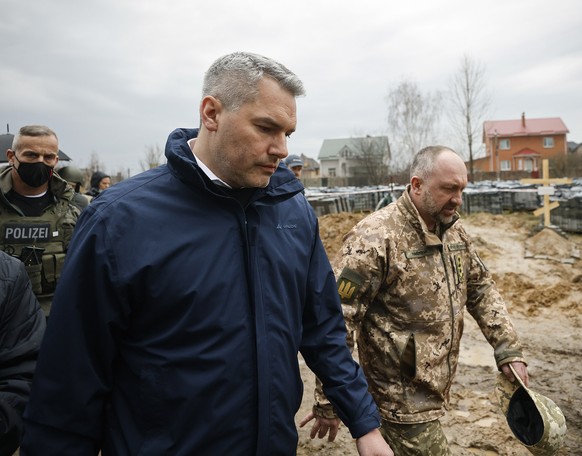epa09880778 A handout photo made available by the Austrian Chancellery shows Austrian Chancellor Karl Nehammer looks on mass graves next to a church during a visit to Bucha, near Kyiv, Ukraine, 09 Apr ...