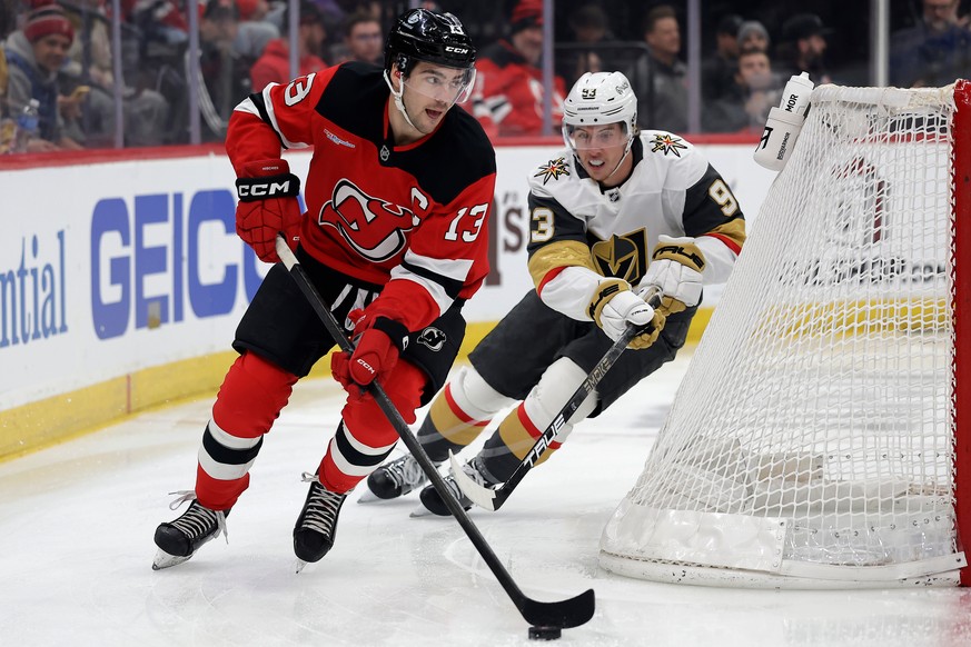 New Jersey Devils center Nico Hischier (13) controls the puck past Vegas Golden Knights right wing Mitch Marner (93) during the first period of an NHL hockey game Friday, Dec. 5, 2025, in Newark, N.J. ...