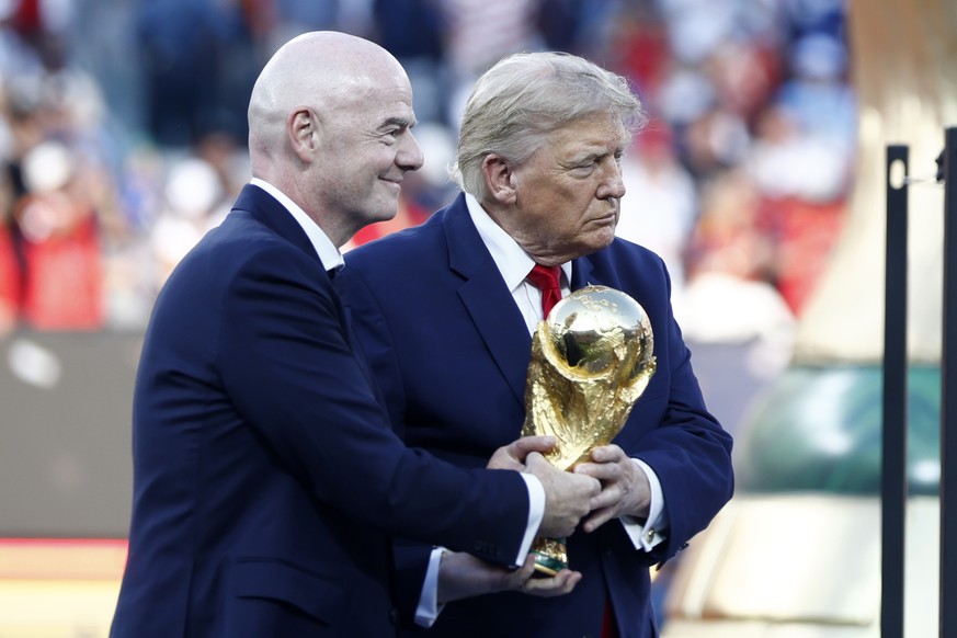 epa13122000 FIFA President Gianni Infantino (L) and US President Donald J. Trump carry the World Cup Trophy to the podium during the awards ceremony after the FIFA World Cup 2026 final match Spain aga ...