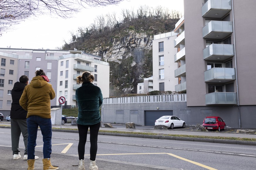 Des personnes regardent des blocs de pierre et de la terre tomber de la paroi lors du minage d&#039;un bloc rocheux de la falaise de la Barme ce mardi 2 decembre 2025 a Collombey-Muraz. (KEYSTONE/Cyri ...
