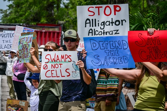 Demonstrators hold signs as they protest the construction of an immigrant detention center, dubbed &quot;Alligator Alcatraz,&quot; in the Everglades near Ochopee, Florida, on June 28, 2025. Florida be ...