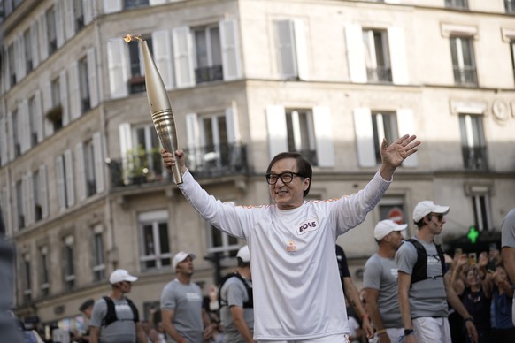 Jackie Chan carries the Paralympic torch Wednesday, Aug. 28, 2024 in Paris. (AP Photo/Aurelien Morissard)