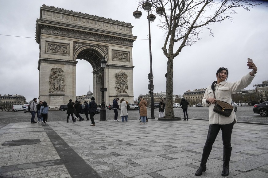 Une touriste fait un selfie devant l'Arc de Triomphe, sur les Champs Elysées.
