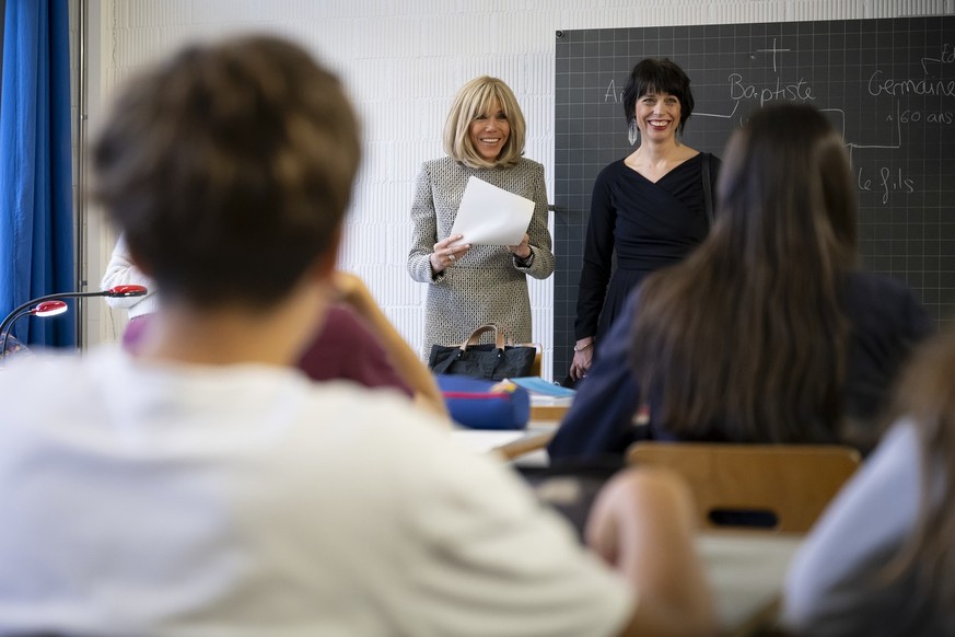 France's First Lady Brigitte Macron, left, and Switzerland's First Lady Muriel Zeender Berset, right, laugh during a visit by a class of students at the public school of french language (Eco ...