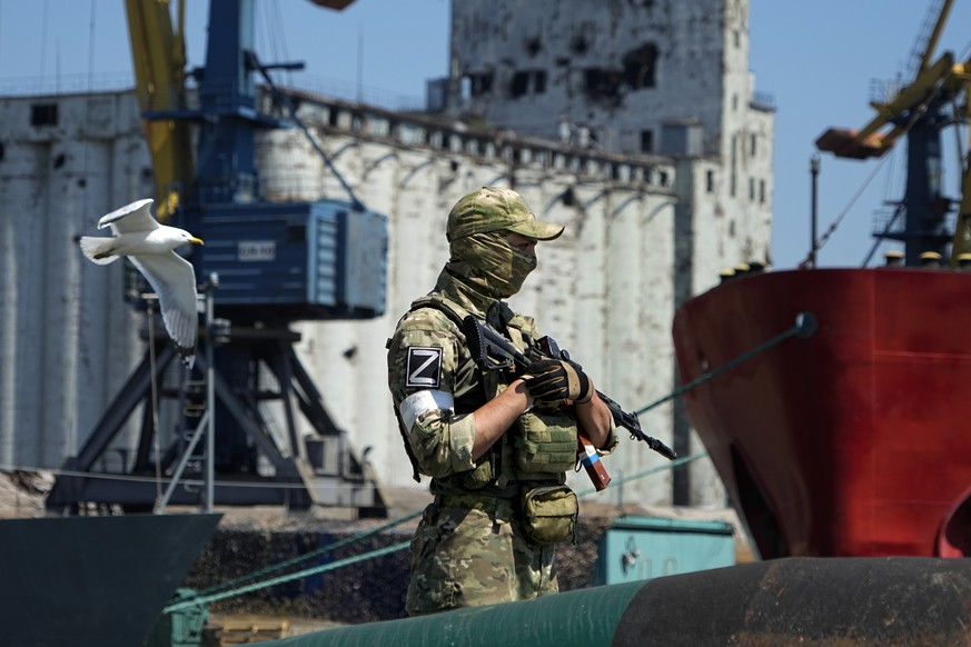 A Russian soldier guards a pier with the grain storage in the background at an area of the Mariupol Sea Port which has recently started its work after a heavy fighting in Mariupol, on the territory wh ...