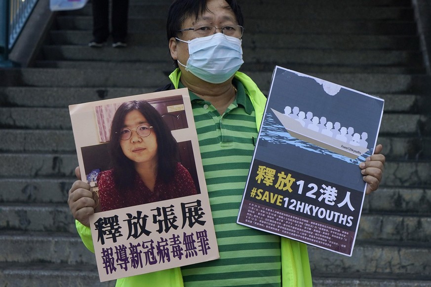 A pro-democracy activist holds placards with the picture of Chinese citizen journalist Zhang Zhan outside the Chinese central government&#039;s liaison office, in Hong Kong, Monday, Dec. 28, 2020. Zha ...