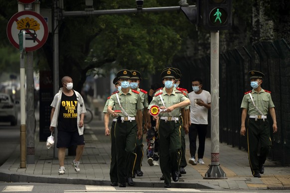 Chinese paramilitary police wearing face masks walk across an intersection in Beijing, Tuesday, July 5, 2022. (AP Photo/Mark Schiefelbein)
