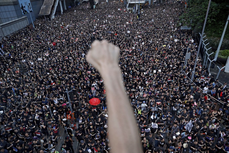 FILE - A protester raises a fist near protesters marching on the streets against an extradition bill in Hong Kong on June 16, 2019. From the military suppression of Beijing���s 1989 pro-democracy prot ...